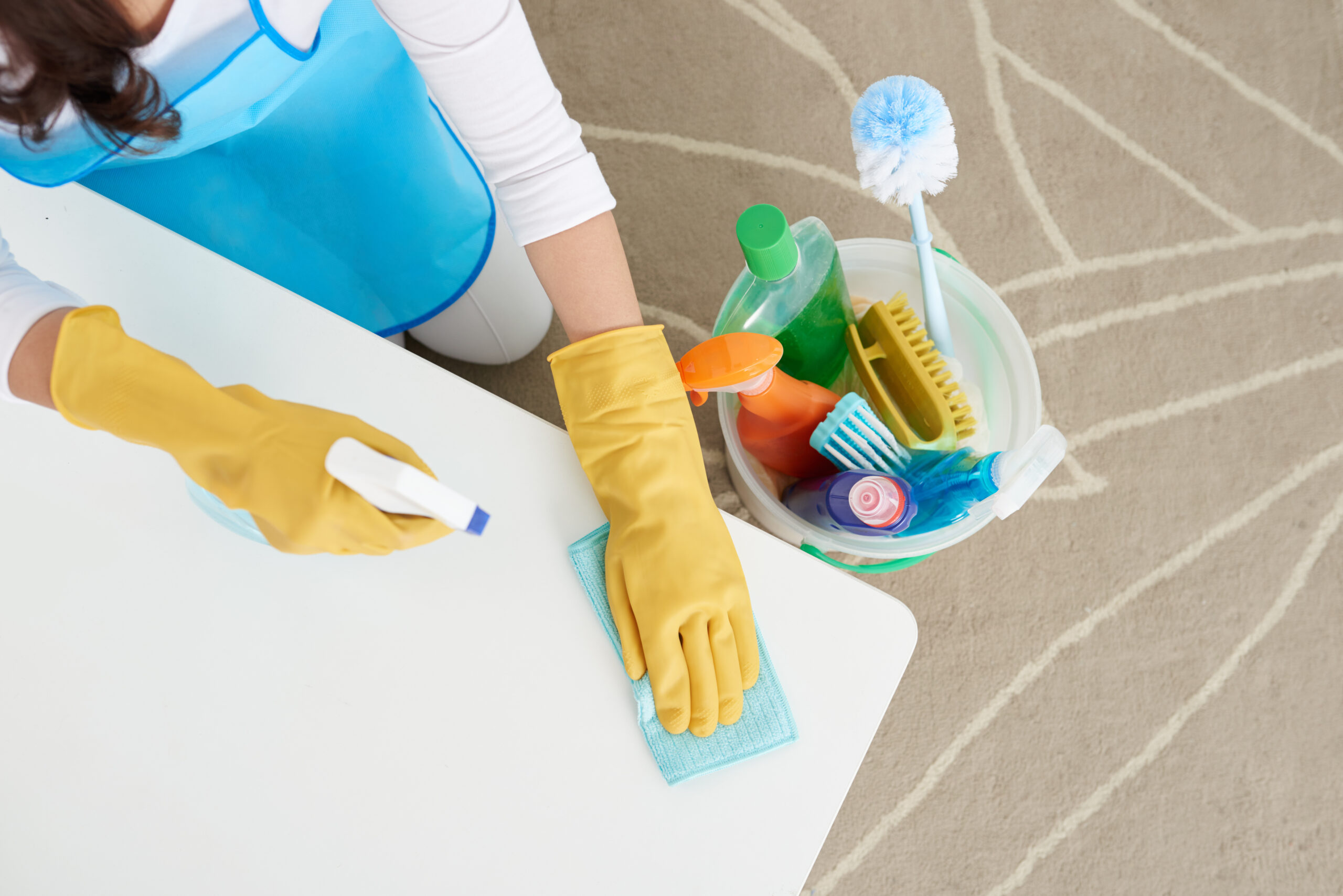 Woman cleaning table with detergent, view from above